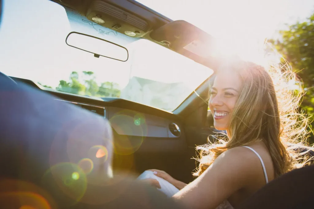 Conductrice souriante au volant de sa voiture, de nouveau assurée après une résiliation