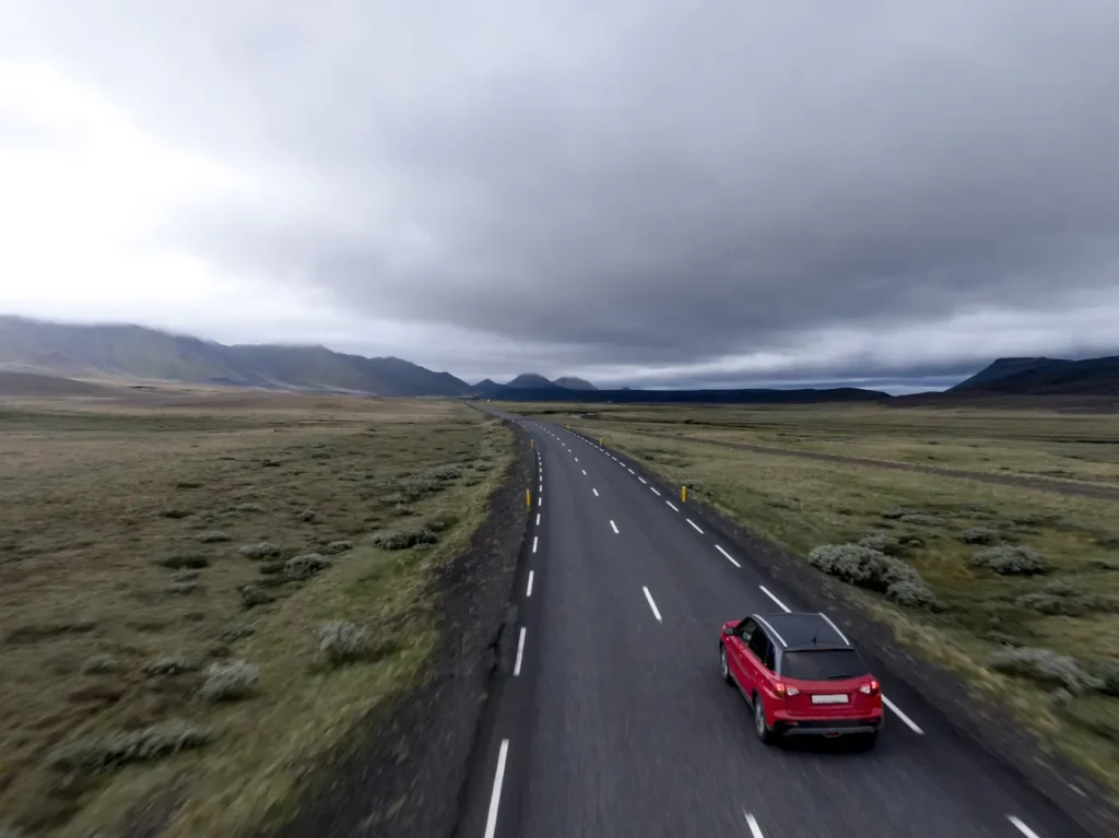 Voiture rouge roulant sur une route asphaltée